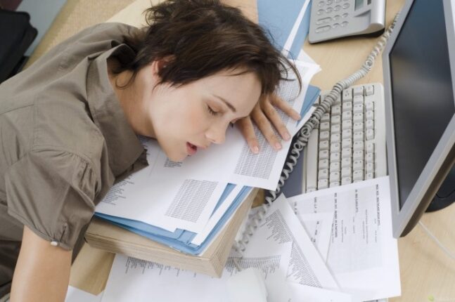 mujer durmiendo sobre escritorio